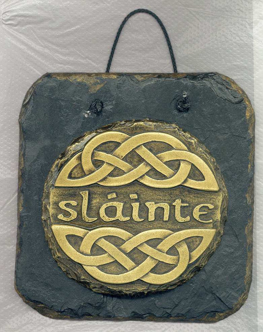 The Slainte Wall Plaque - This wall plaque features the Irish word Slainte, which means cheers or good health. This term is an every day toast used in Irish pub - The design on this plaque also incorporates a Celtic knotwork design which embellishes the Gaelic word. -  The design is coldcast in brass and then mounted onto a slate wall hanging plaque 125mm x 125mm in size.